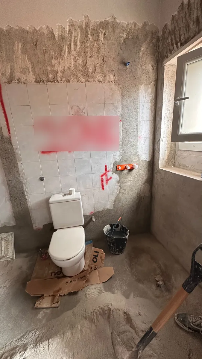 Casa de banho em Benfica, Lisboa, antes da remodelação, com paredes picadas e canalização nova a instalar