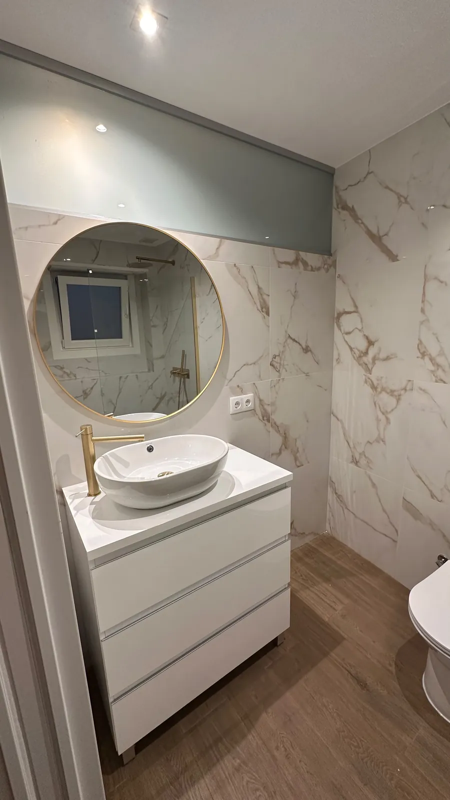 Casa de banho remodelada em Benfica, Lisboa: móvel com lavatório de pousar, torneira dourada e espelho redondo