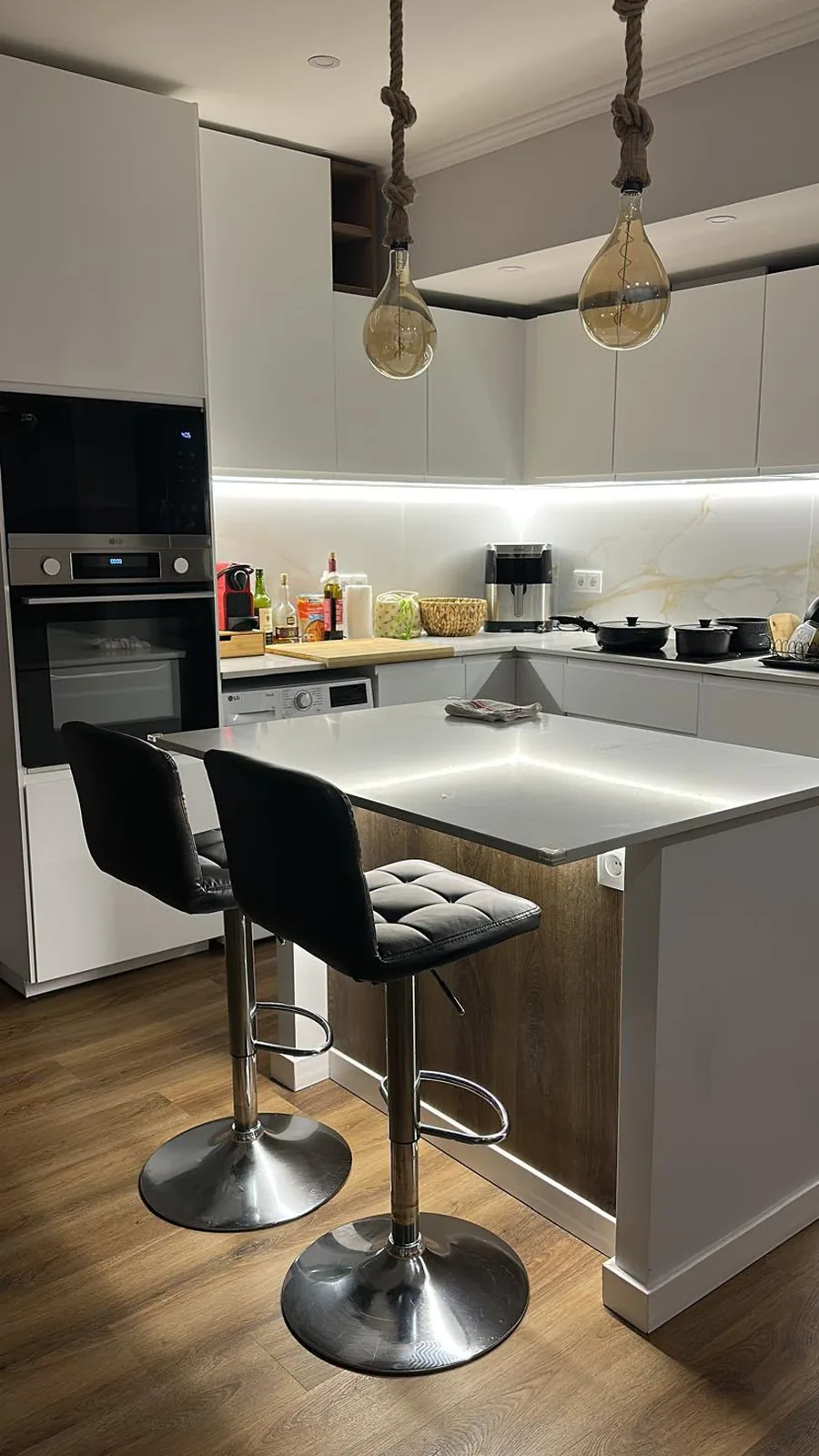 Cozinha remodelada em Algés, Oeiras: ilha com bancos altos, luz LED sob os armários e salpicadeira efeito mármore