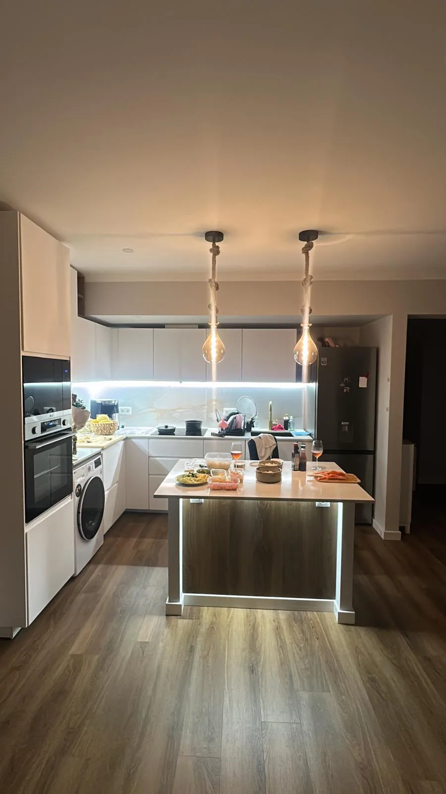 Cozinha remodelada em Algés, Oeiras: ilha em madeira com luz LED, candeeiros de corda e pavimento efeito madeira