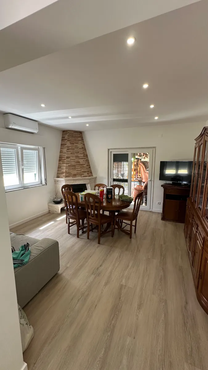 Sala remodelada em Caneças, Odivelas: pavimento novo, teto falso com focos e lareira revestida a pedra